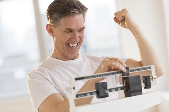 Excited Man Clenching Fist While Using Weight Scale